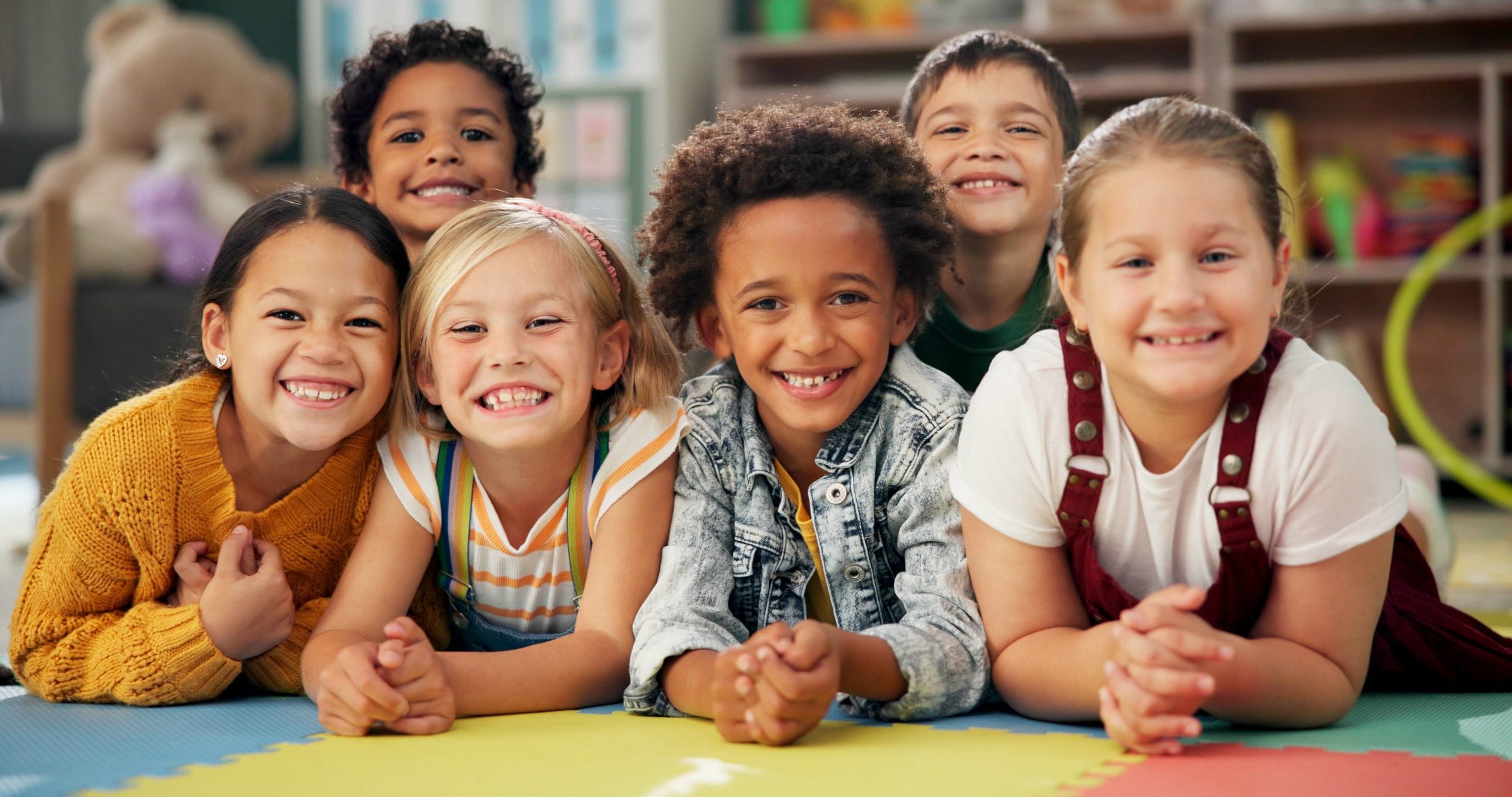 A group of happy children smiling together in a classroom.